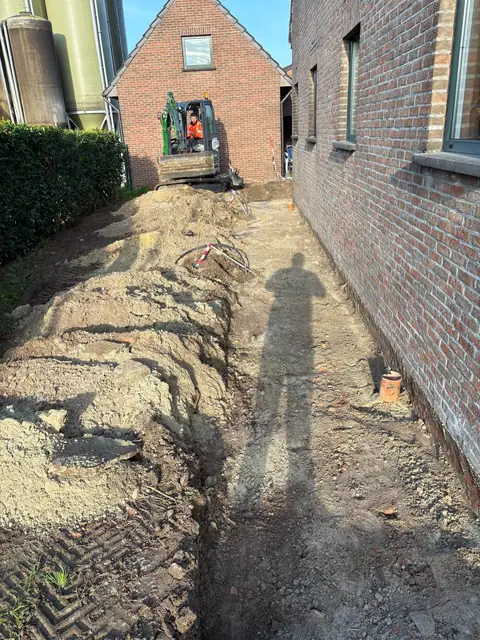 Uitgegraven zijpad naast de woning, klaar voor de fundering