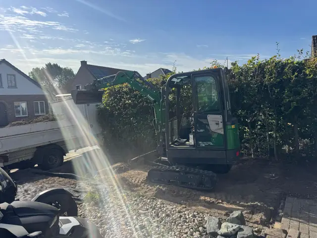 Minigraver aan het werk bij het zijpad