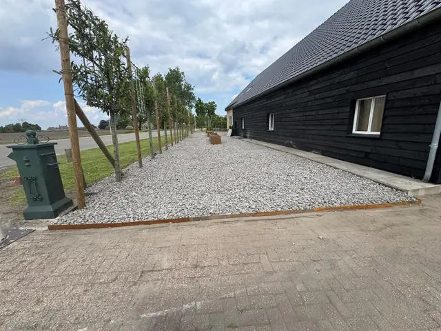 Grindvlak met bomenrij langs de schuur