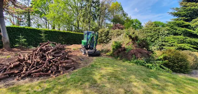 Minigraver ruimt struiken op in de tuin